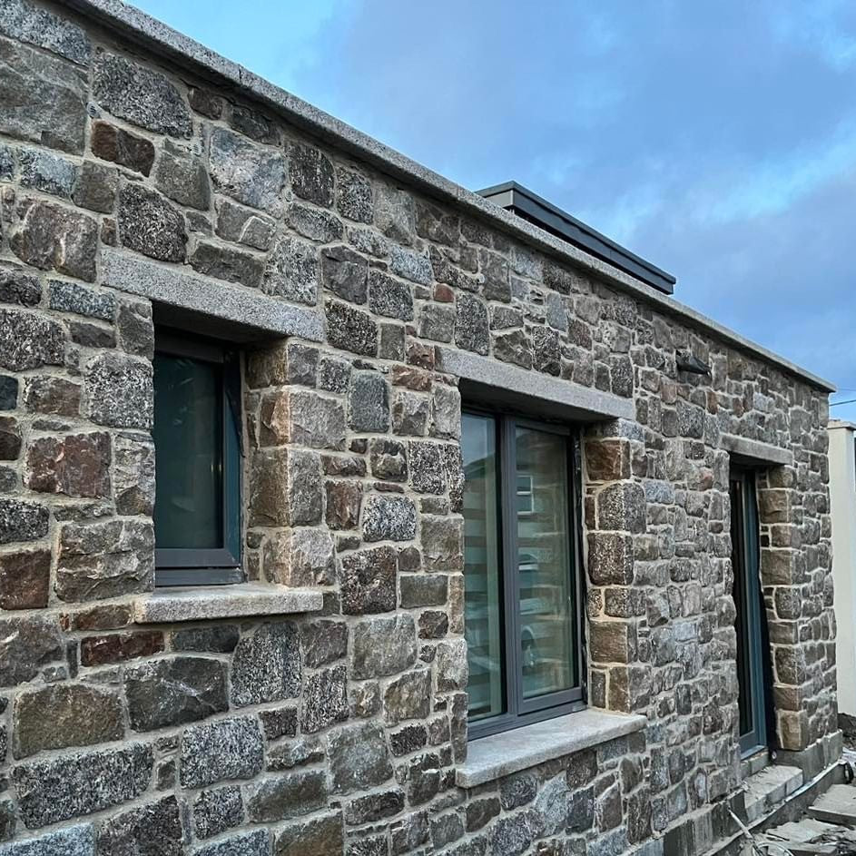 Stone building with modern windows featuring bespoke silver granite lintels and sills. 