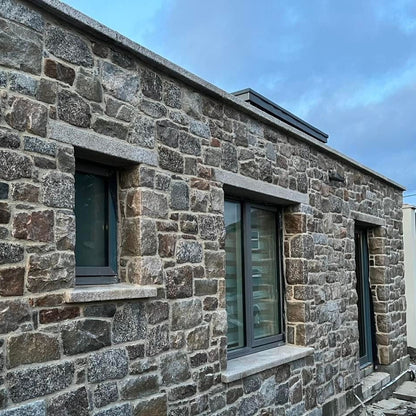 Stone building with modern windows featuring bespoke silver granite lintels and sills. 