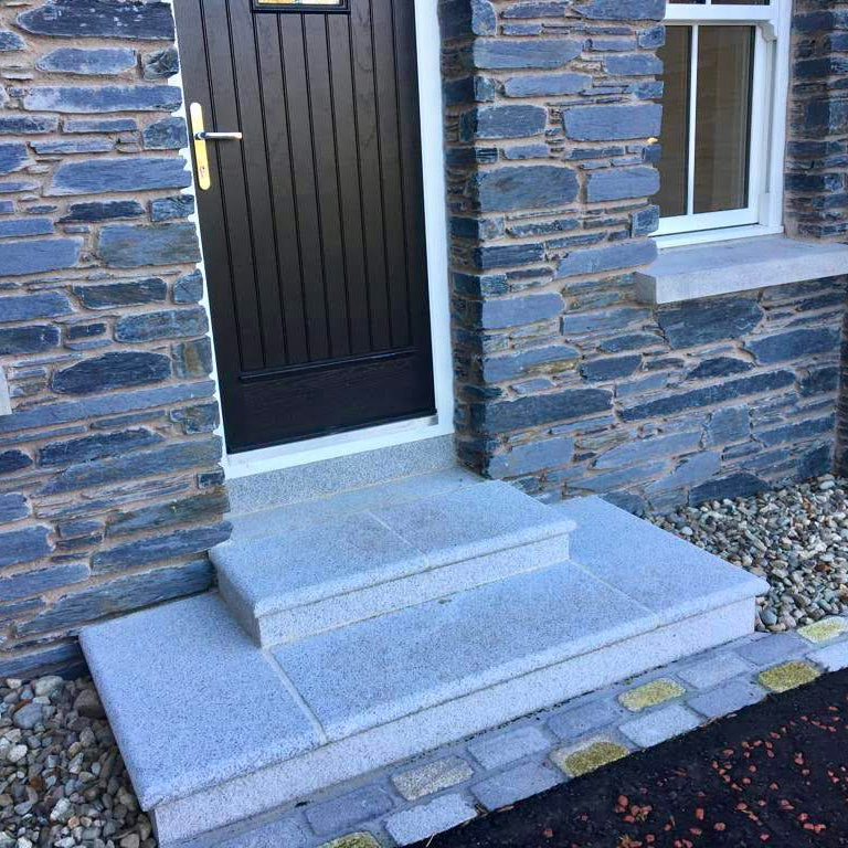 Silver Granite Stone steps leading to a door on a stone house. 