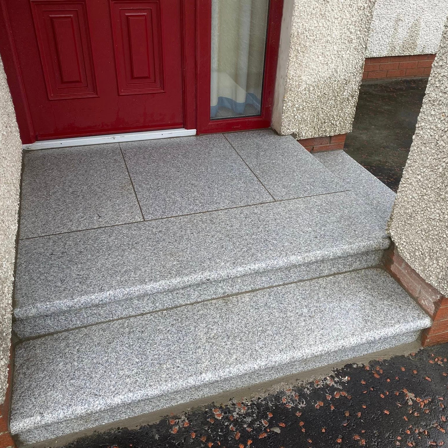 Silver Granite Step and Riser Sets  leading to a red door on a building with textured walls.
