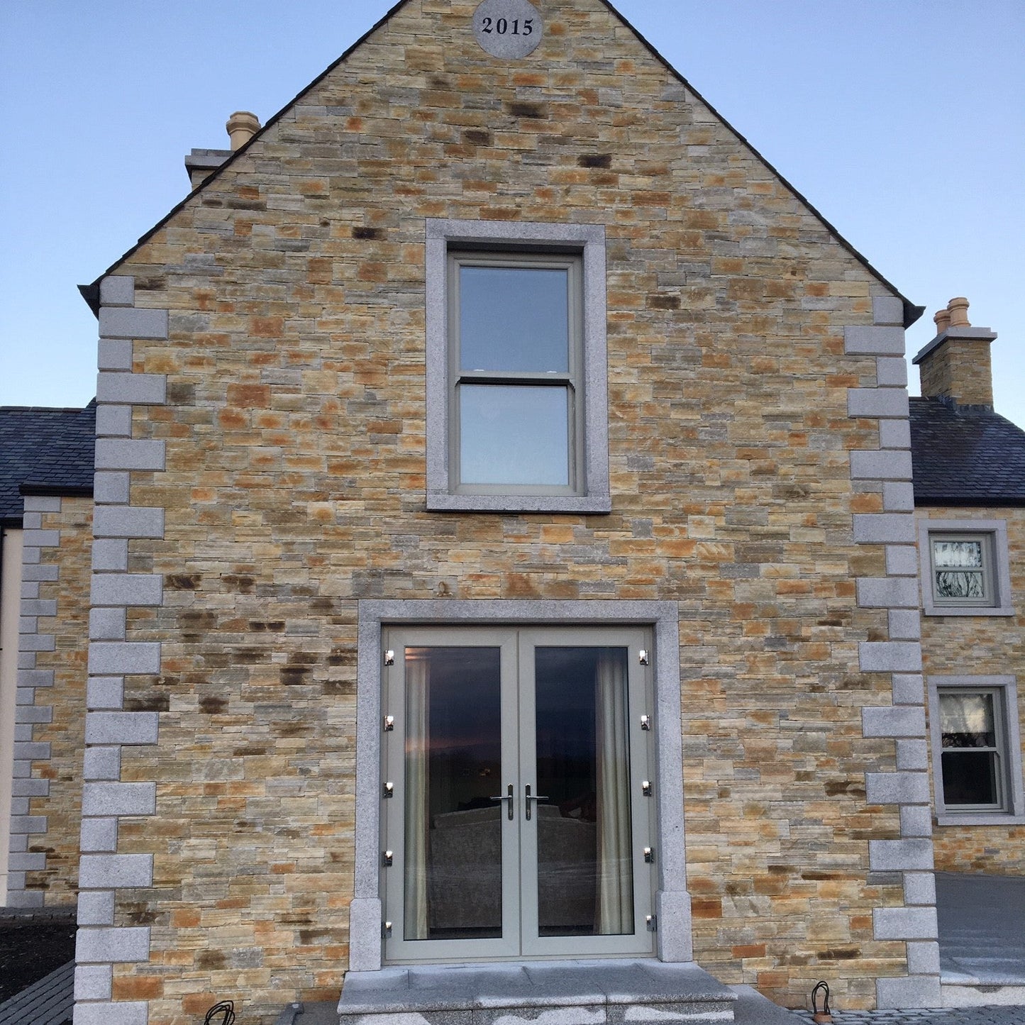 Stone building with a modern door and window design completed with bespoke Silver Granite Window and Door Surround. 