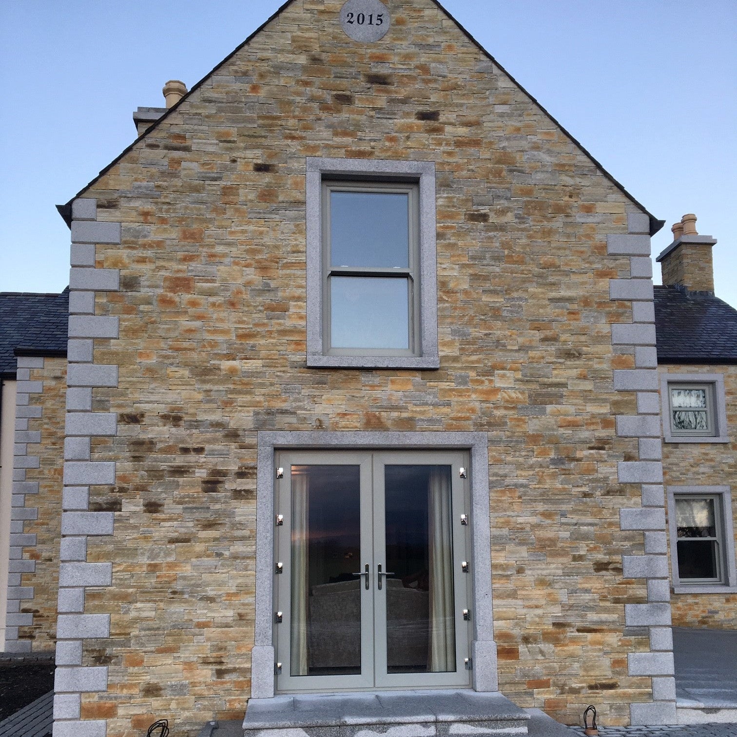 Stone building with a modern door and window design completed with bespoke Silver Granite Window and Door Surround. 