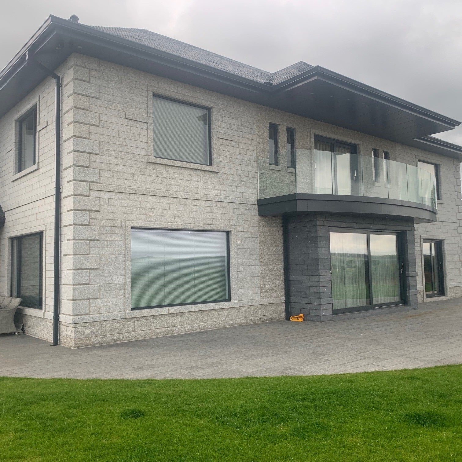 Modern house with stone façade and large Silver Granite Window Surrounds on a cloudy day