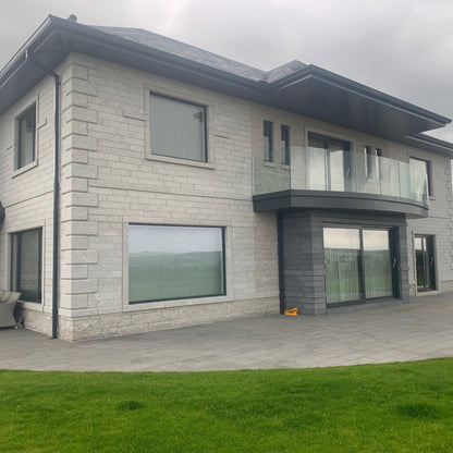 Modern house with stone façade and large Silver Granite Window Surrounds on a cloudy day