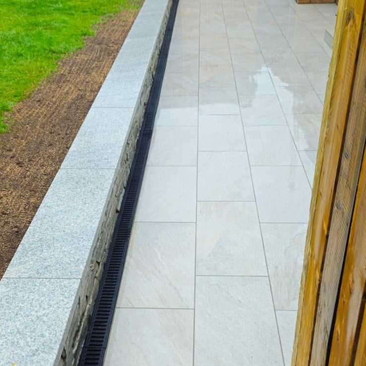 Paved pathway completed using Silver Quartz Diva Range Porcelain Paving with a drain and grass on the side