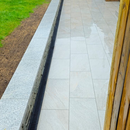 Paved pathway completed using Silver Quartz Diva Range Porcelain Paving with a drain and grass on the side
