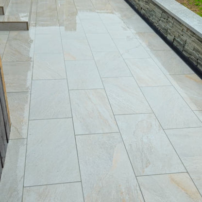 Silver Quartz Diva Range Porcelain Paving on a patio with a stone wall in the background