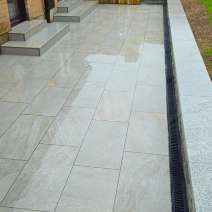 Outdoor patio with large stone tiles and a drain channel. Paving is Silver Quartz Diva Range Porcelain Paving Tiles. 