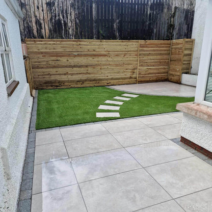 Small patio area with stepping stones leading to a circular patio area and artificial grass. Paving is Silver Street Range Porcelain Paving Tiles. 