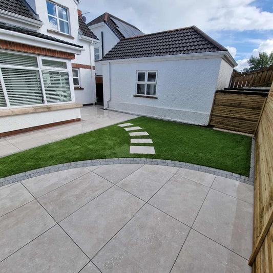 White two storey house with circular patio area and stepping stones. Paving is Silver Street Range Porcelain Paving Tiles. 