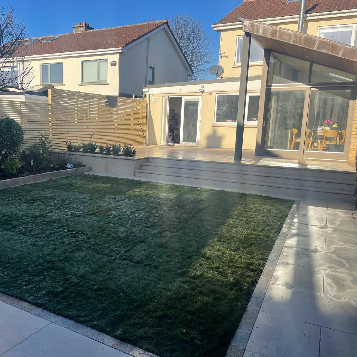 Backyard with grass, patio, and house exterior. Paving is Sinai Pearl Porcelain Paving tiles. 