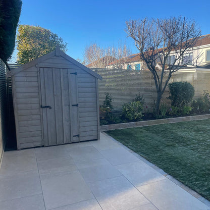 Backyard with a wooden shed, paved patio, and grass area on a clear day. Paving is Sinai Pearl Porcelain Paving tiles. 