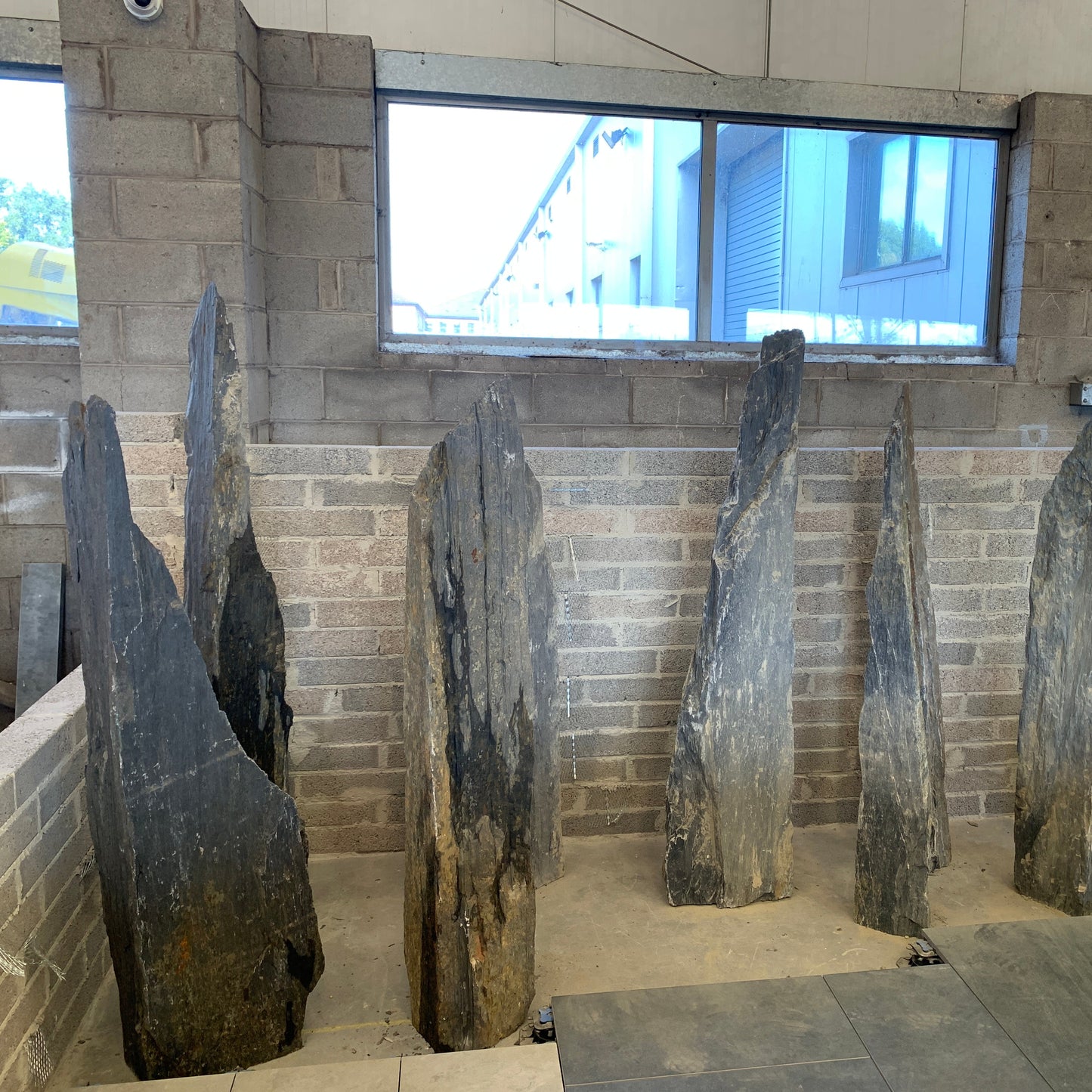 Slate Monoliths displayed against a  wall with large window.