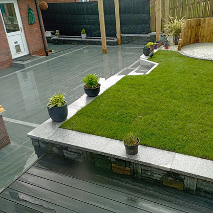 Patio area and raised garden with lots of potted plants dotted around. Paving is Smokey Jewel Range Porcelain Paving. 