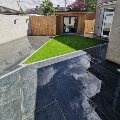 Another angle showcasing an outdoor room cladded in wood with a triangular garden. Paving is Station Black Jewel Range Porcelain Paving. 