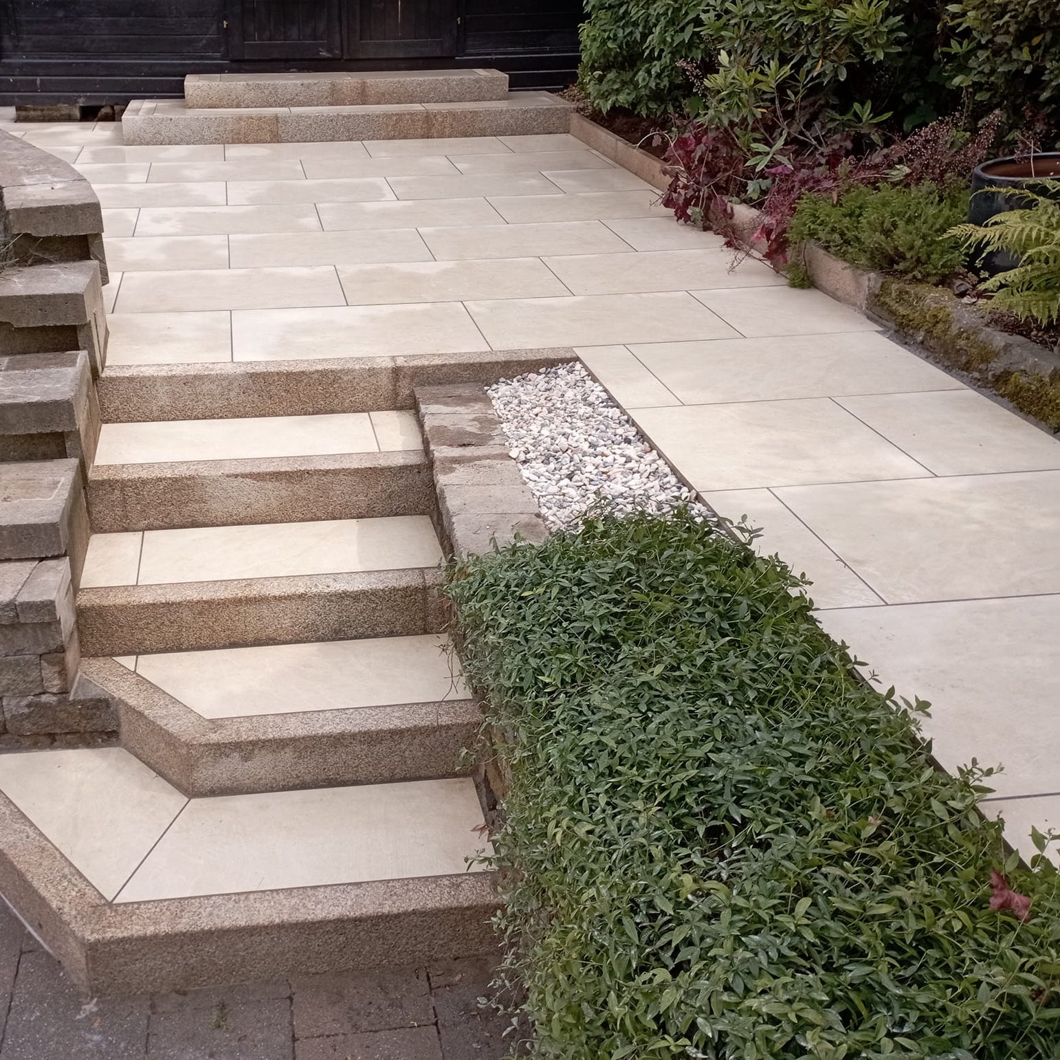 An outdoor installation of Station White porcelain paving tiles in a garden setting, with a warm white colour.