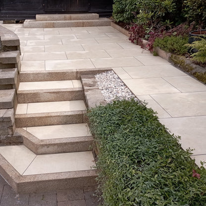 An outdoor installation of Station White porcelain paving tiles in a garden setting, with a warm white colour.