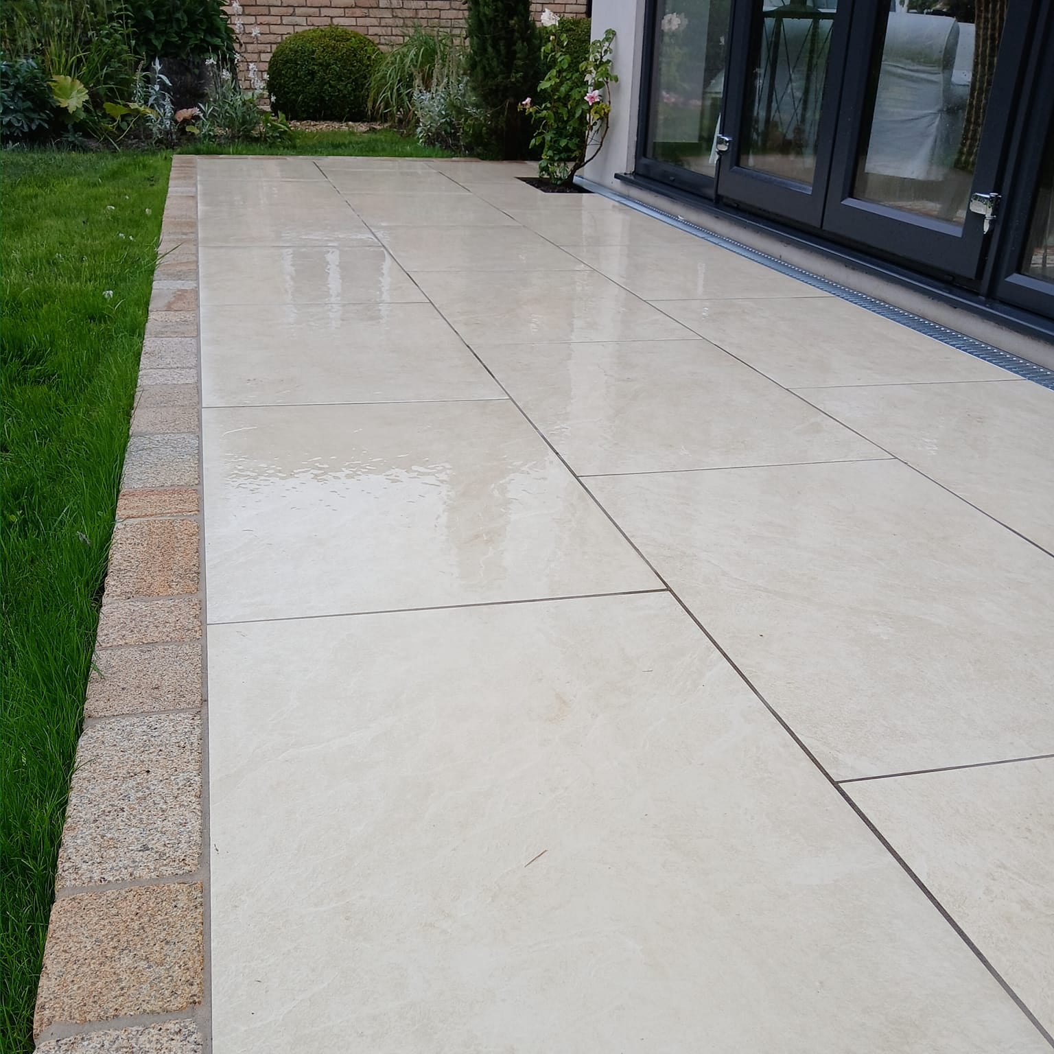 Close up of Station White Porcelain Paving in small patio area bordered by Gold Granite Cobbles. 