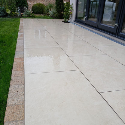Close up of Station White Porcelain Paving in small patio area bordered by Gold Granite Cobbles. 