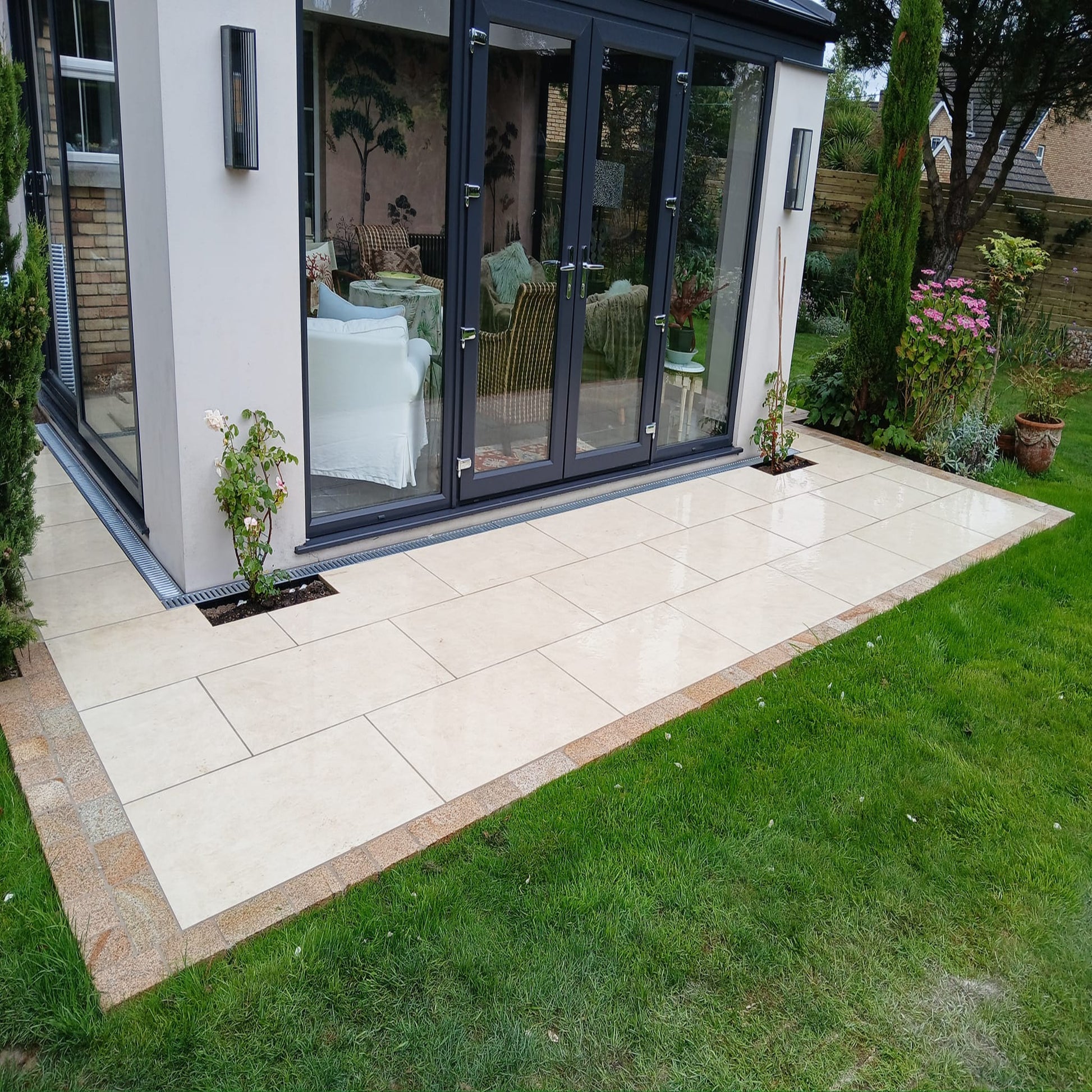 A small garden patio featuring Station White porcelain paving tiles and gold granite cobbles. 