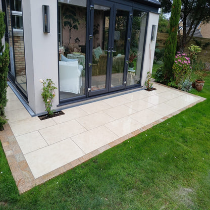 A small garden patio featuring Station White porcelain paving tiles and gold granite cobbles. 