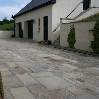 Patio area with view of garage and wall featuring Tinted Mint Sandstone Paving installed in mixed sizes and cobbles. 