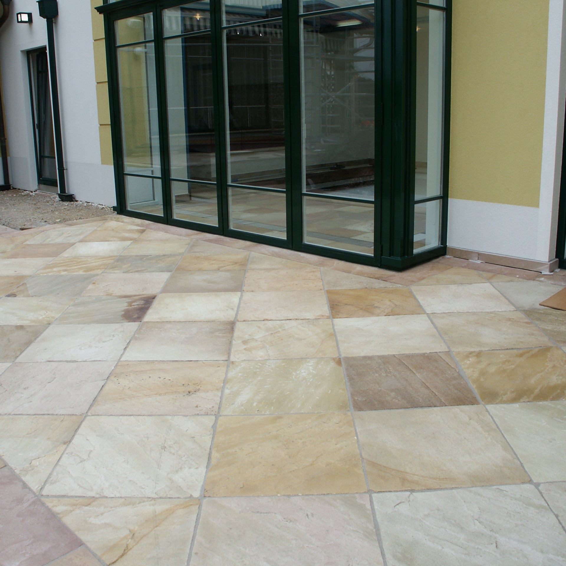 Paved area with a glass structure in the background. Paving is Tinted Mint Sandstone in 600 x 600mm size. 