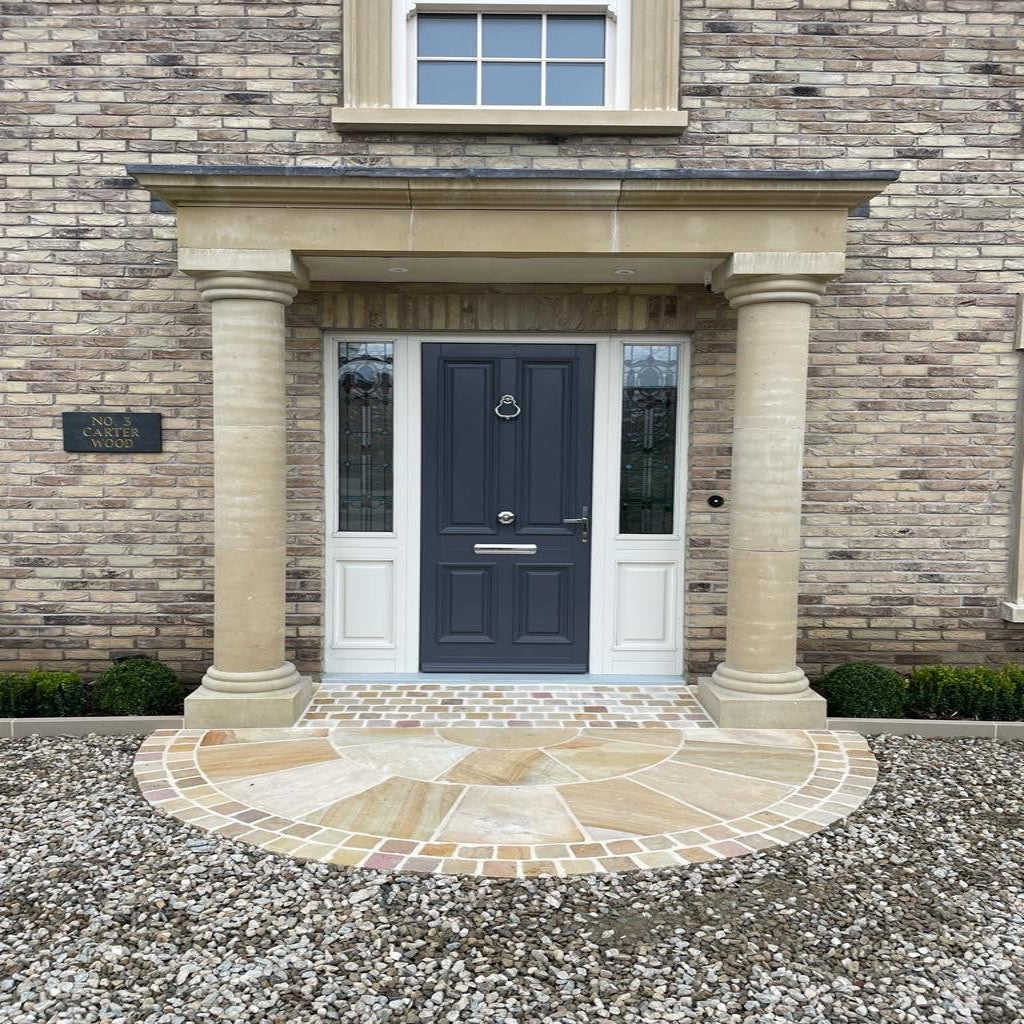 A 2.5m diameter Tinted Mint Sandstone circle installed with Tinted Mint Sandstone Cobbles at the doorway of a brick house creating an elegant entrance.