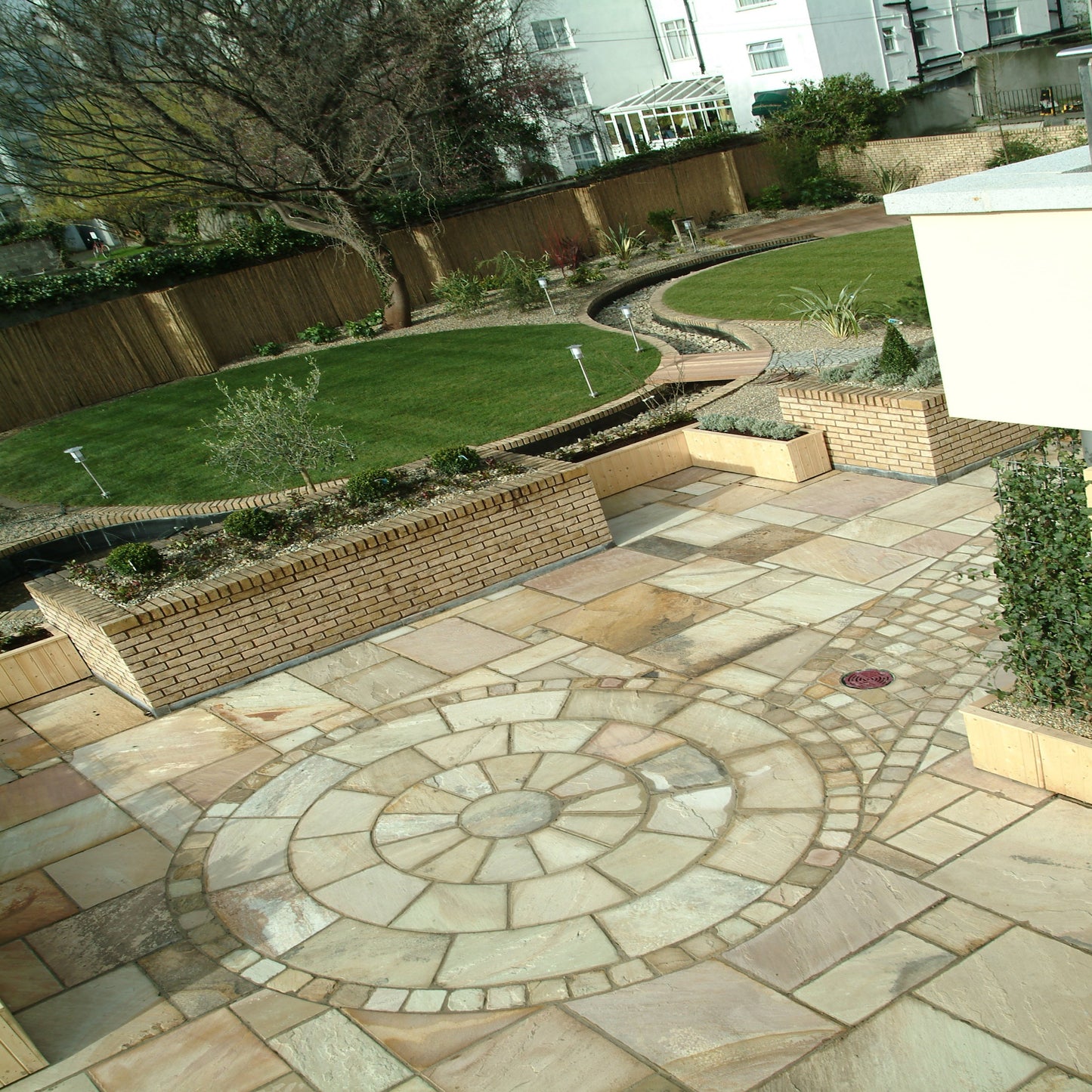 Large patio featuring 3m Tinted Mint Sandstone Circle with matching Tinted Mint Sandstone Patio Pack Paving and Cobbles. 