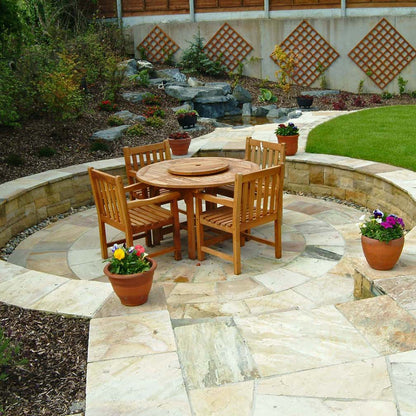 Outdoor patio with wooden furniture and decorative elements. Patio features a 4m Tinted Mint Sandstone Paving Circle. 
