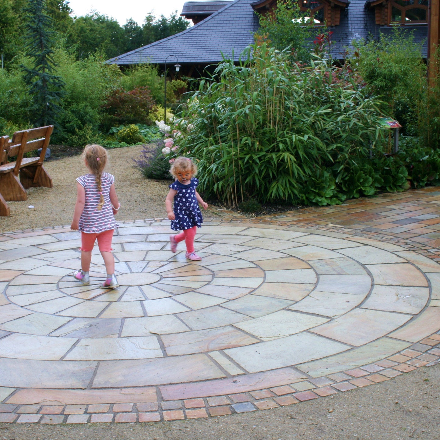 Children playing on a large 5m Tinted Mint Sandstone Paving Circle. 