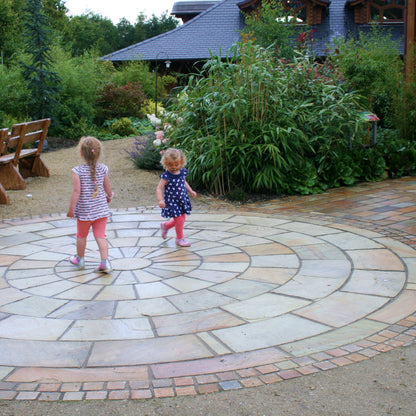 Children playing on a large 5m Tinted Mint Sandstone Paving Circle. 