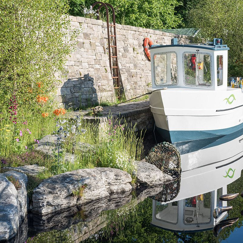 Show garden featuring a boat and waterworn limestone karst stones in the water. 