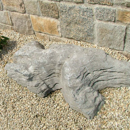 Rockery area featuring waterworn limestone karst stones against a stone wall. 