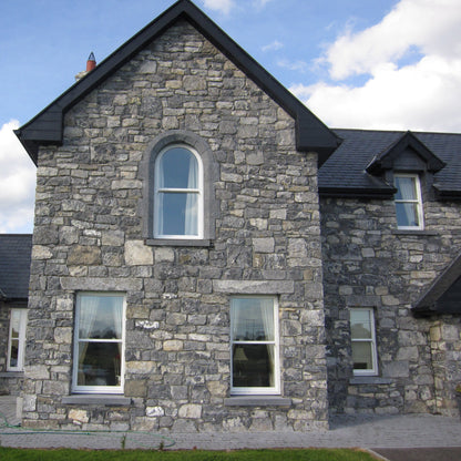 White Limestone house with black roof against a blue sky