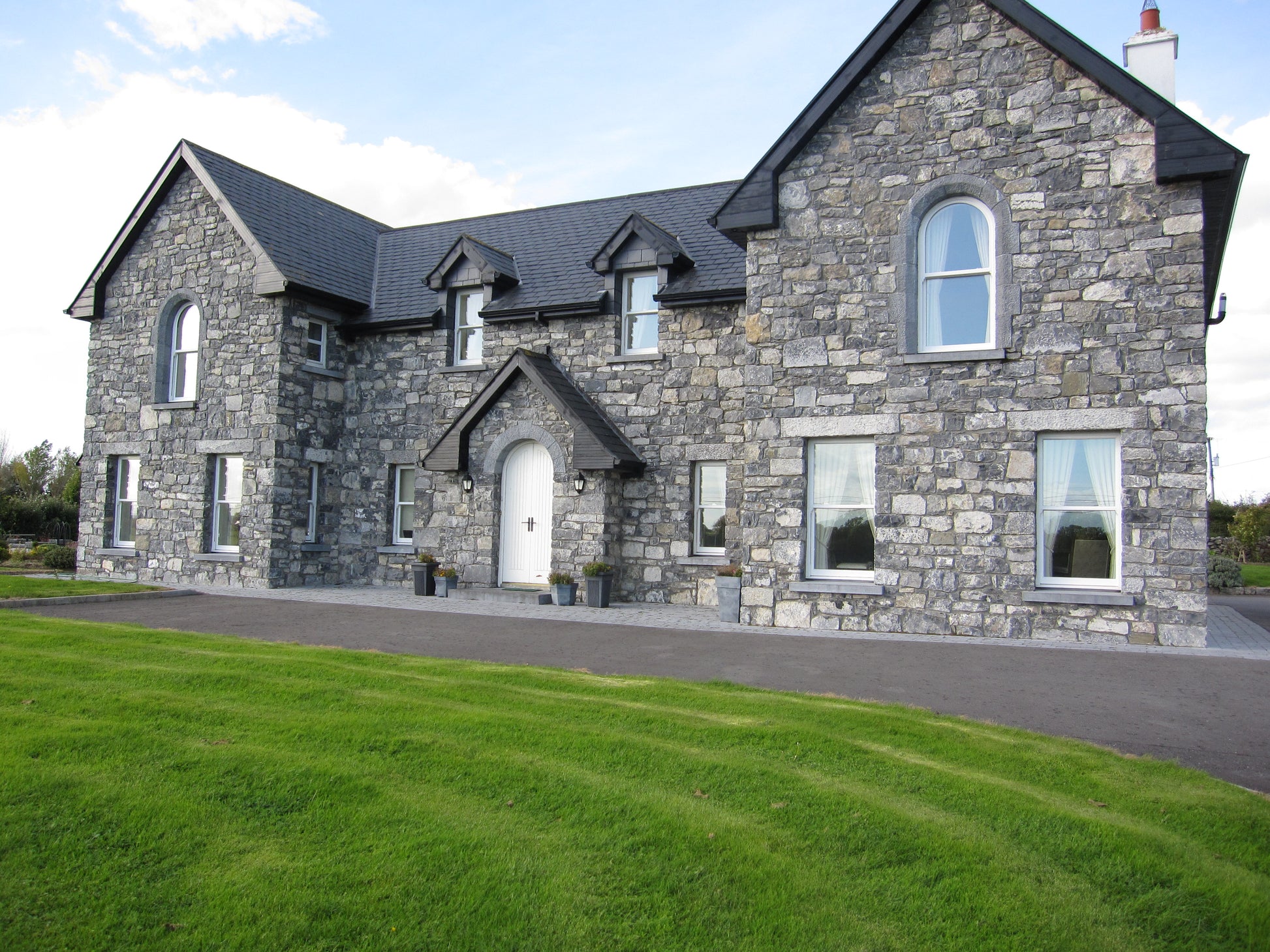 Large white limestone house with a well-maintained lawn and driveway.