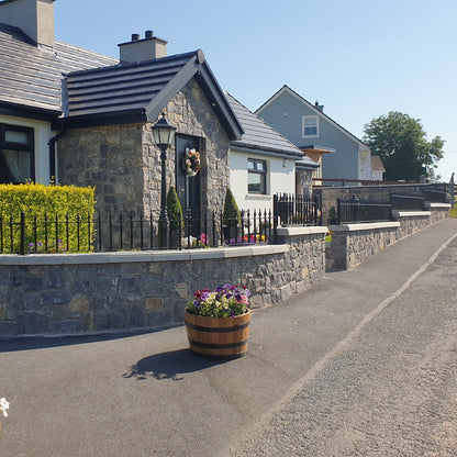 Cottage with flower pots on a sunny day. Porch and boundary wall in white limestone building stone. 