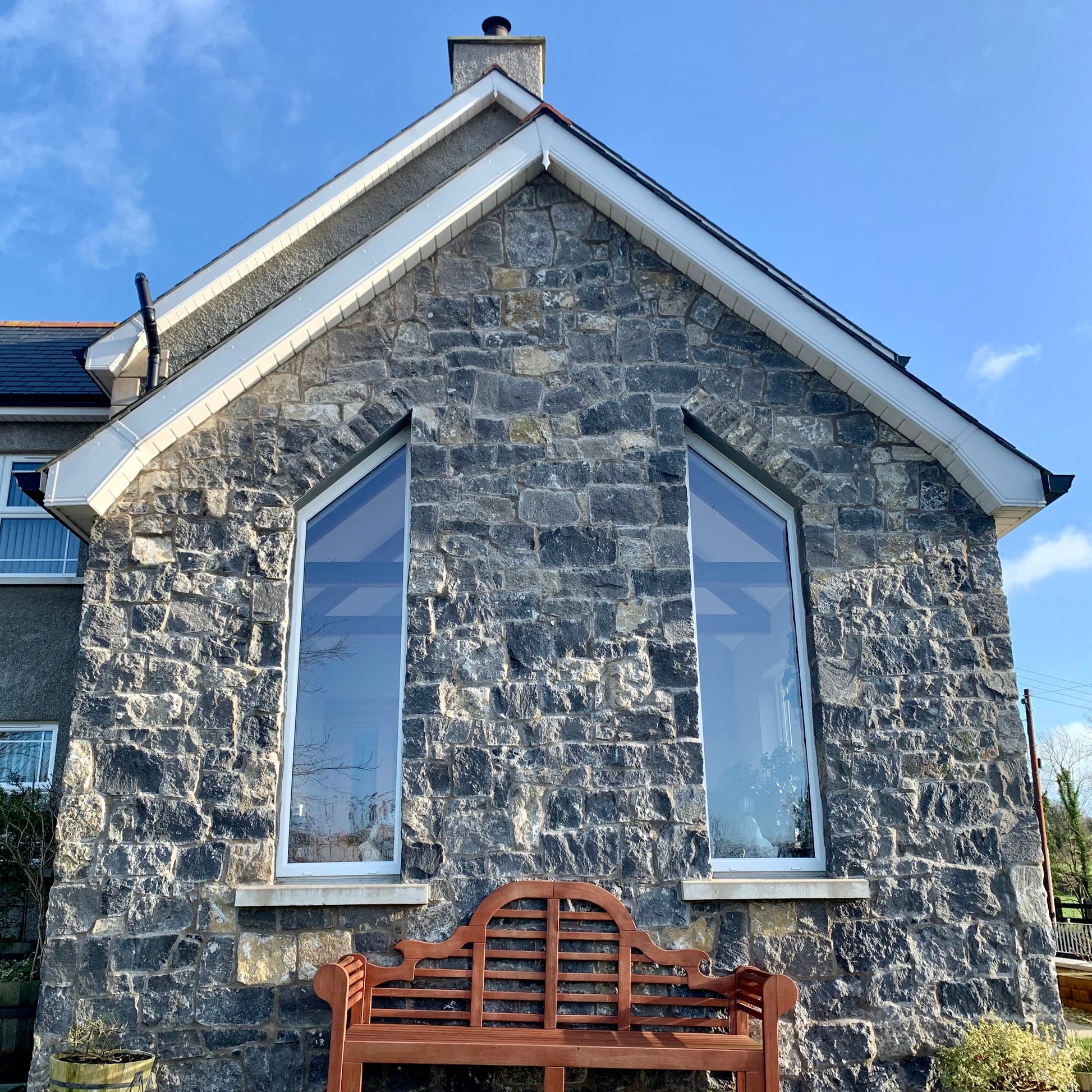Stone façade featuring white limestone stoneer cladding and a brown bench. 