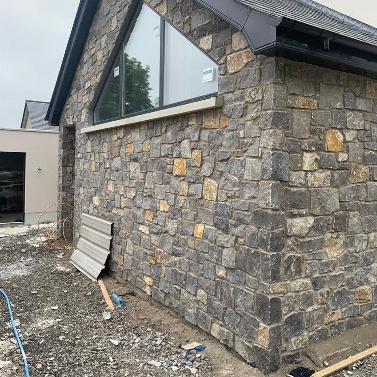 New build house with a stone façade with a triangular window. Stonework is White Limestone Stoneer Cladding. 