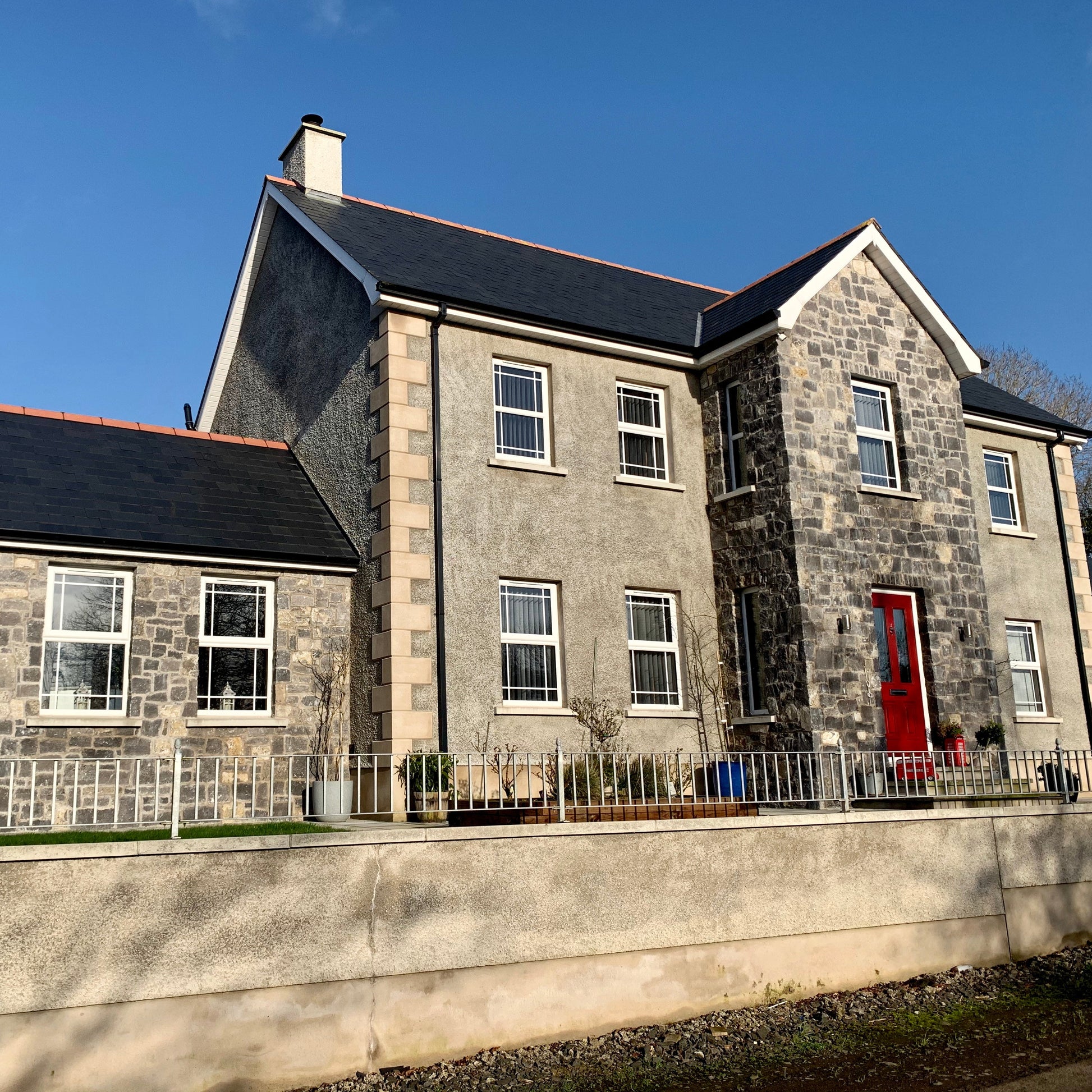 Two storey house with stone walls in White Limestone Stoneer Cladding on a sunny clear day. 