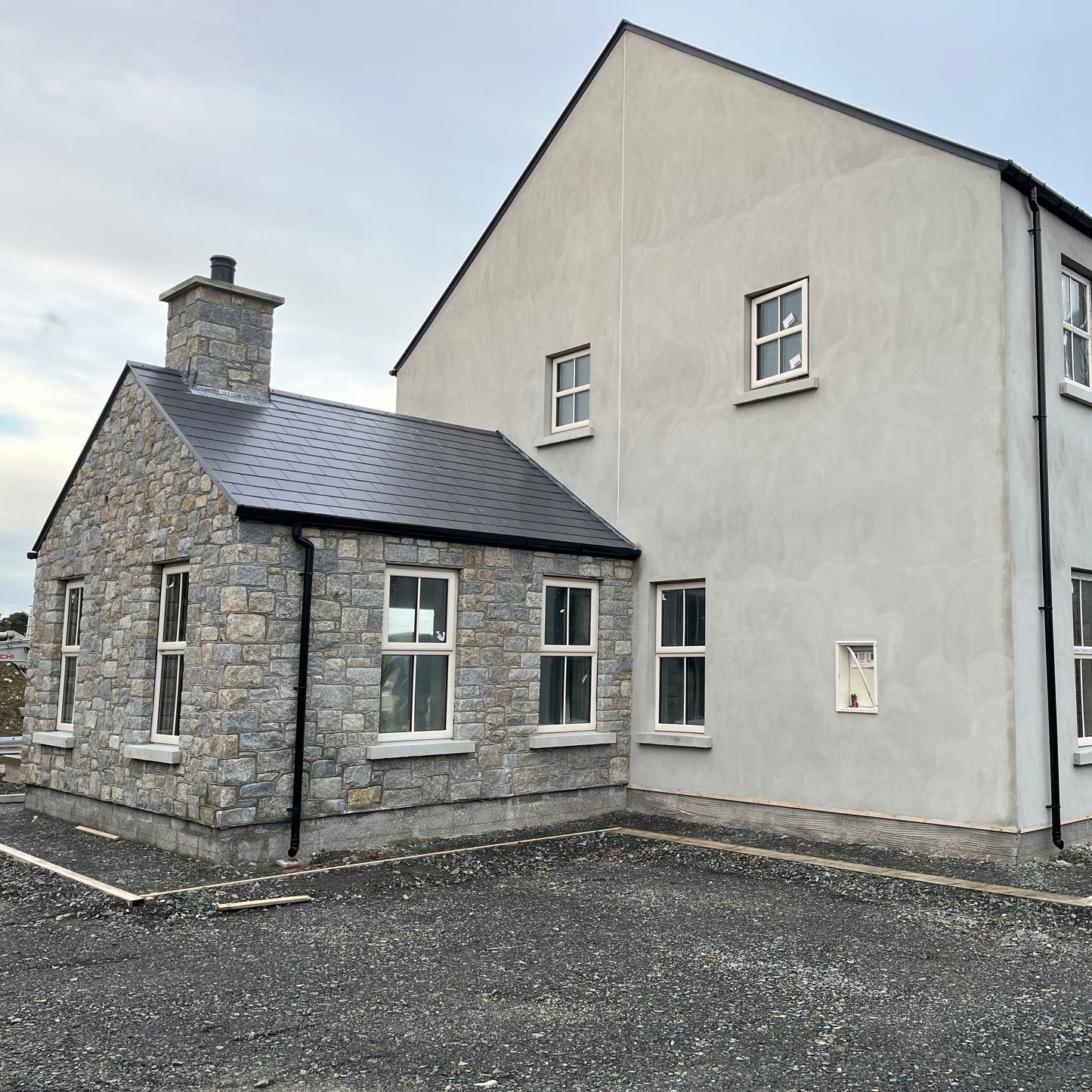 Modern house with stonework in Wicklow Granite and white exterior on a clear day 
