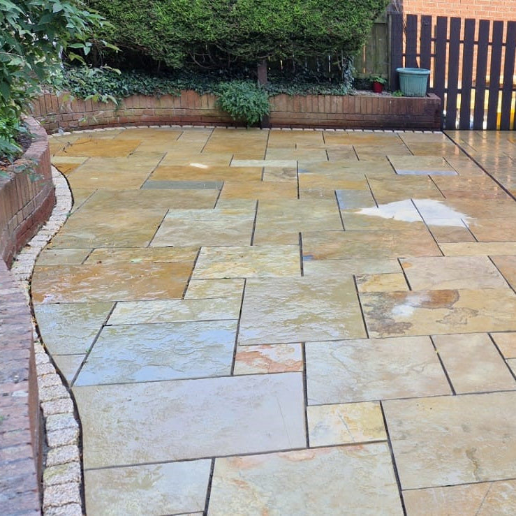 Yellow Limestone Patio completed using Machined Patio Packs. Surrounded by red brick wall and hedging. 