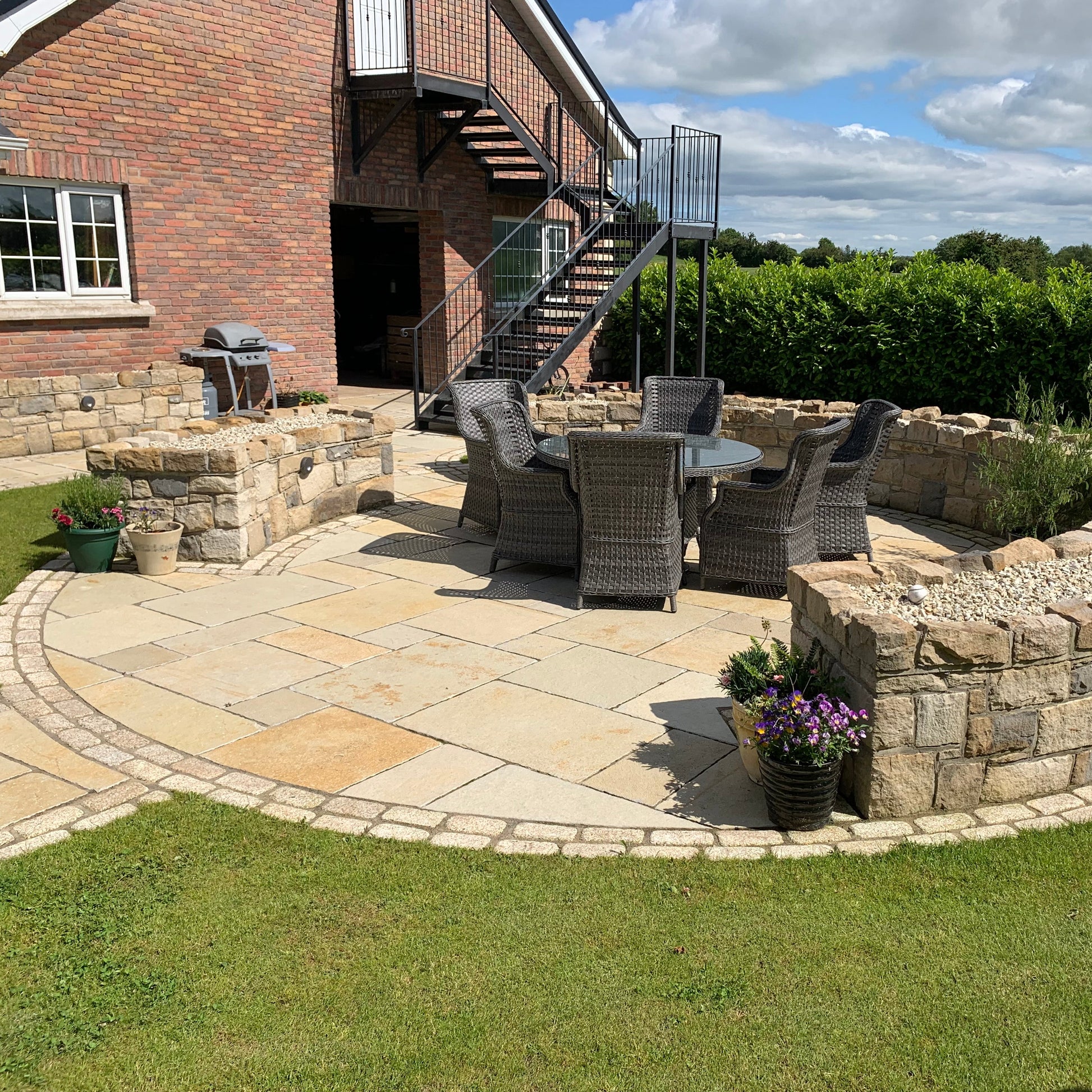 Circular stone seating area featuring stone walling and Yellow Limestone Tumbled Paving and Gold Granite Cobbles. 